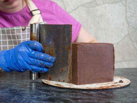 pastry chef girl makes chocolate cake smeared with ganache