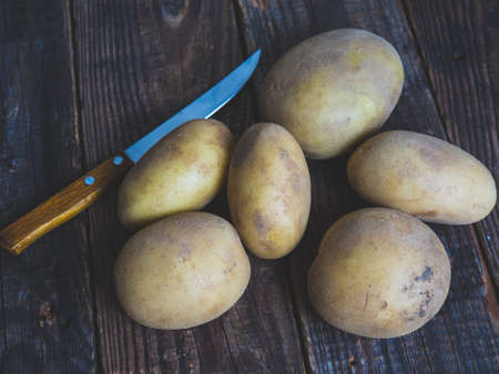 Raw organic golden potatoes in a wooden cage on a wooden tableの写真素材