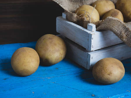 Raw organic golden potatoes in a wooden cage on a wooden tableの写真素材