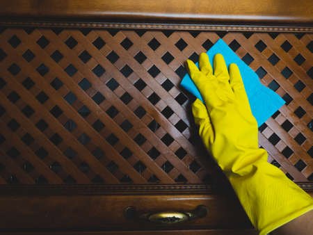 the hand of a girl in protective gloves wipes the kitchen furniture with a blue cloth, the concept...