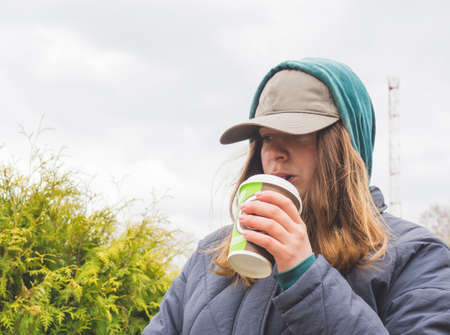 a girl walks in the park and drinks coffee