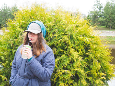 a girl walks in the park and drinks coffee