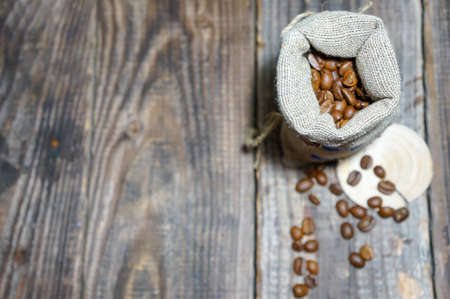 Bag of coffee on a wooden table. Coffee beans are poured. Top view, place for text. Coffee...