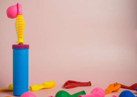 Plastic hand pump next to the pink balloon with. Preparing for the holiday. Organization of the birthday party. Decorator tool on a pink backgroundの写真素材