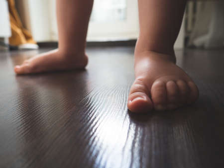 Children's feet take their first steps. The first steps of a child.の写真素材