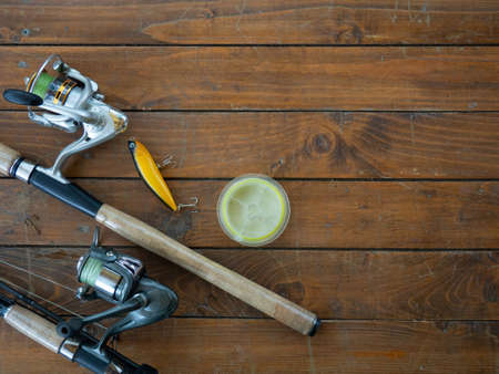 background fishing gear and fishing rods. fishing rod, spinning rod and various baits on a wooden...