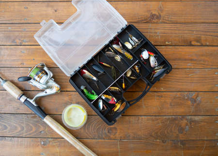 background fishing gear and fishing rods. fishing rod, spinning rod and various baits on a wooden table with a place for textの写真素材