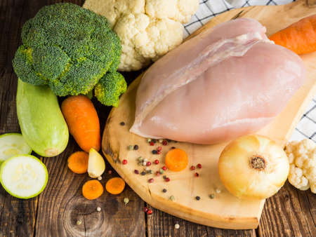 fresh chicken breast and vegetables on rustic wooden backgroundの写真素材