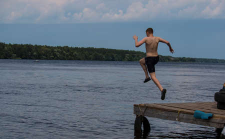 guy jumping from the pier into the lake