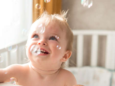 one-year-old child cheerfully plays with soap bubbles
