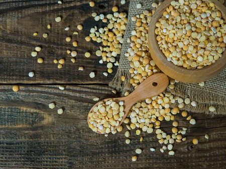 dry peas in a wooden bowl on an old wooden table close-up with copy spaceの写真素材