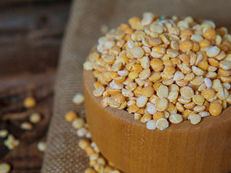dry peas in a wooden bowl on an old wooden table close-up with copy spaceの写真素材