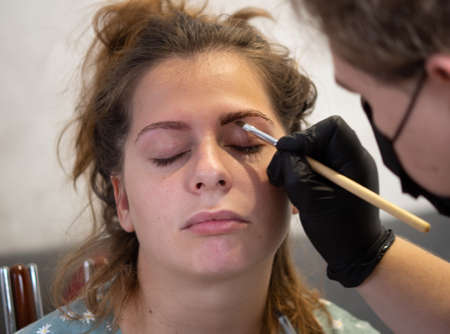 Make-up beautician applies henna paint to eyebrows. Professional face care.