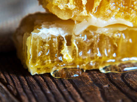 bee honeycomb with honey close-up on an old wooden tableの写真素材