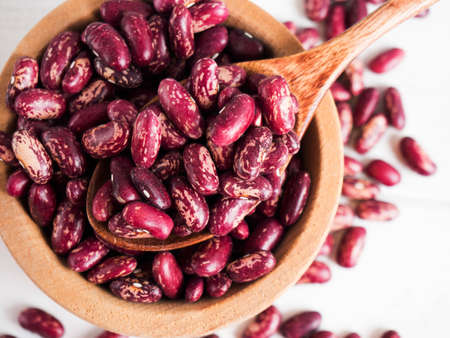 red beans in a wooden bowl on a white wooden table, copy space