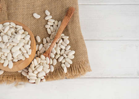 white beans in a wooden spoon on a white wooden table, copy spaceの写真素材