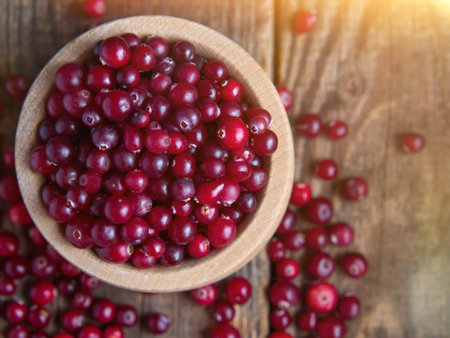 Ripe fresh cranberries in a wooden bowl on a rustic table top.