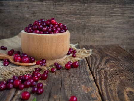 Ripe fresh cranberries in a wooden bowl on a rustic table top.の写真素材