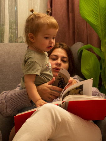 mom and daughter read a book in a chair lifestyleの写真素材