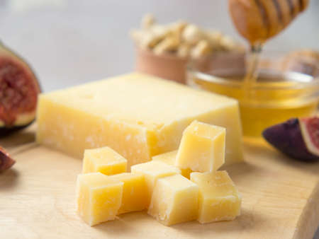 Pieces of aged cheese, nuts, figs and honey on a cutting board,