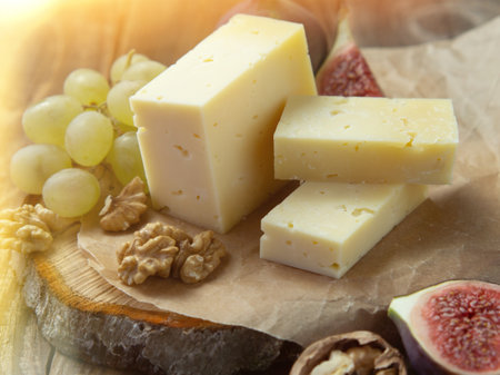 farm quality cheese lie on a wooden board surrounded by figs. grapes and nuts. close-up on an old wooden tableの写真素材