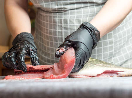 girl cook cuts pike on the kitchen tableの写真素材