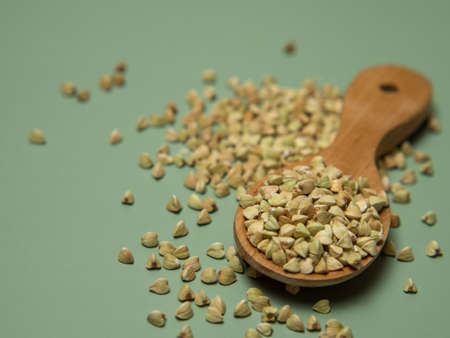 Peeled buckwheat seeds in wooden spoon isolated on green backgroundの写真素材