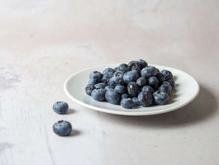 blueberries on a white saucer on a concrete background