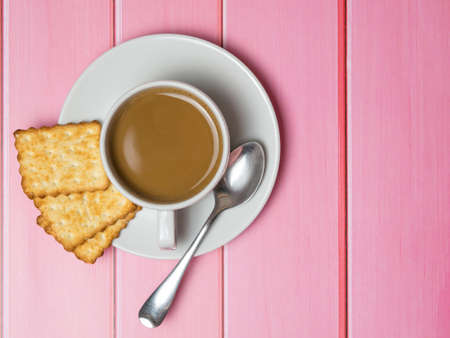coffee with cream and a snack cracker on a pink wooden tableの写真素材