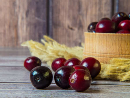 large cranberries in a wooden bowl on a wooden background. Healthy food and nutrition. Place for text.の写真素材