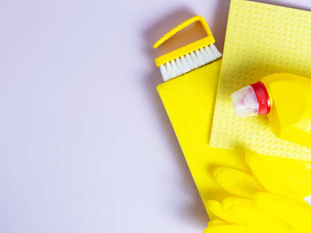 yellow detergent bottle with sponge on folded yellow napkin and yellow rubber gloves on isolated purple background with copyspaceの写真素材