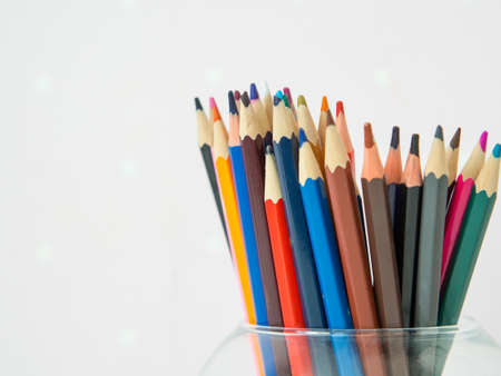 Colorful pencils in a glass jar, on a white background with copy spaceの写真素材