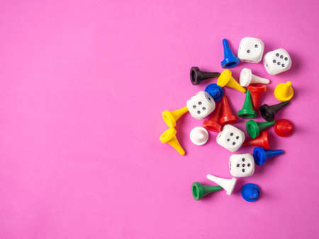 On a pink background, colorful game pieces and cubes are laid out with a place for text, games at...