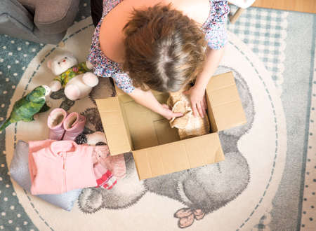 Winter baby clothes donation concept. Woman preparing used old clothes at home.の写真素材