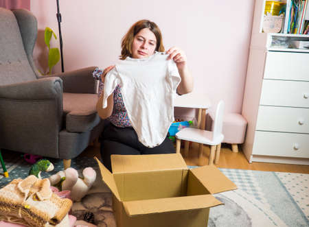 Winter baby clothes donation concept. Woman preparing used old clothes at home.の写真素材
