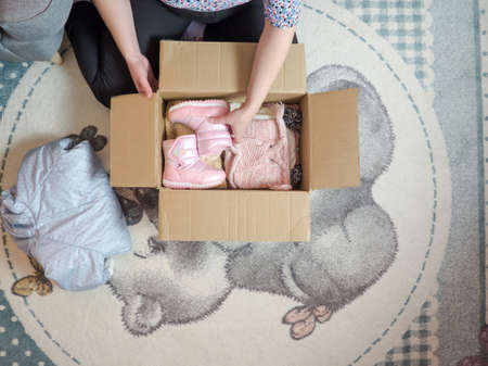 Winter baby clothes donation concept. Woman preparing used old clothes at home.の写真素材