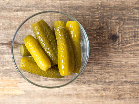 Pickled cucumbers in a bowl on a wooden rustic table and a jar of picklesの写真素材