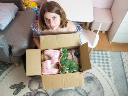 Winter baby clothes donation concept. Woman preparing used old clothes at home.