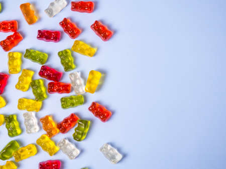 Delicious bright gummy bears on a blue background, flat layの写真素材