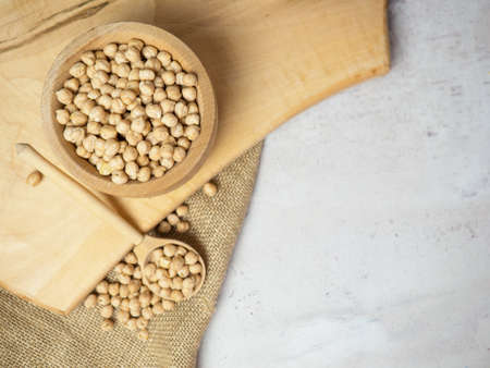 Wooden bowl and wooden spoon full of chickpeas on a light concrete background. close upの写真素材