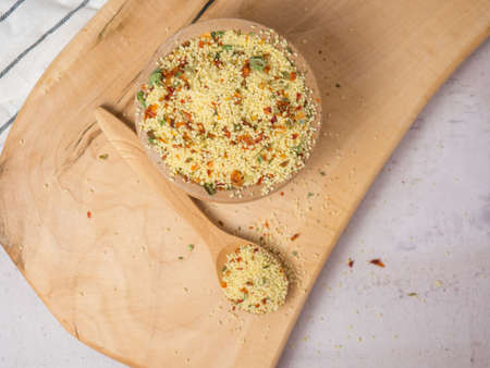couscous mix with spices and tomatoes in a wooden bowl and spoon close-upの写真素材