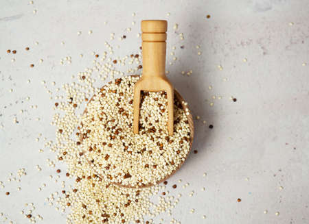 Raw mixed quinoa in bowl and scoop on light concrete background. Healthy and diet superfoodの写真素材