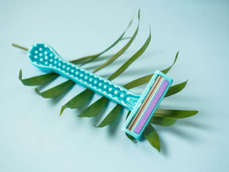 One women's blue razor on a blue background. Spa and women's treatments, hair removal