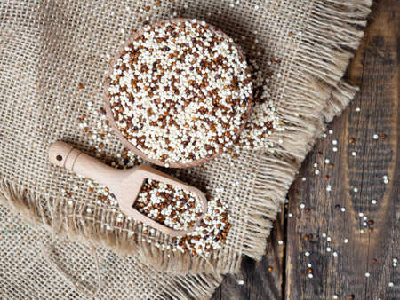 Quinoa in wooden bowl and scoop on rustic background