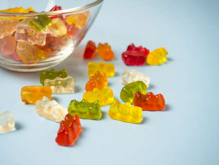 Bowl with tasty bright gummy bears on blue tableの写真素材