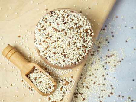 Raw mixed quinoa in bowl and scoop on light concrete background. Healthy and diet superfoodの写真素材