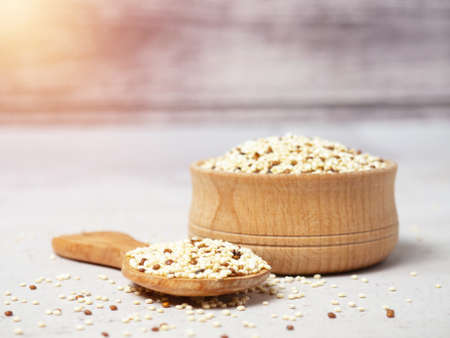 Raw mixed quinoa in bowl and scoop on light concrete background. Healthy and diet superfoodの写真素材