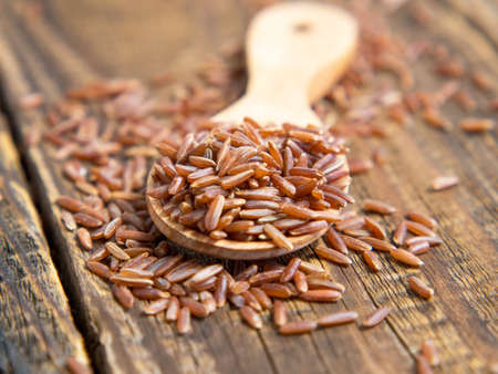 Red rice (brown rice) in a wooden bowl, red rice scattered on the ground.close upの写真素材