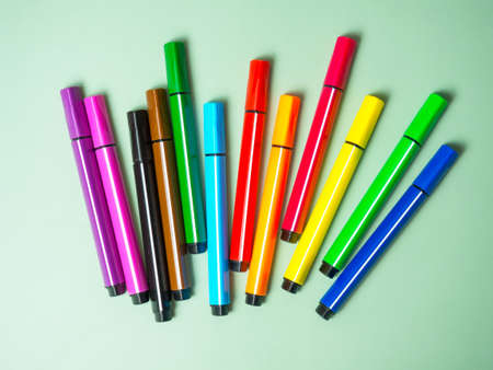 A set of multicolor felt-tip pens, multi-colored felt-tip pens on a green background with space for...