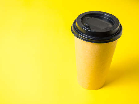 a paper cup of coffee with a closed lid on a bright yellow background.の写真素材